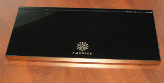 Black AMOUAGE perfume box with gold logo on a wooden surface