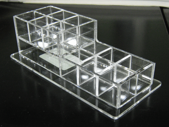 Clear plastic modular organizer on a black surface, with stacked cube compartments and small items inside
