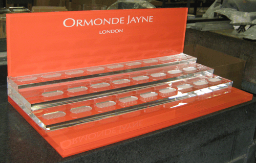 Orange Ormonde Jayne perfume display case with rows of clear bottles on shelves