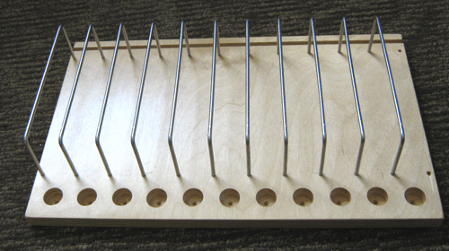 Wooden base with ten upright metal rods and matching circular holes along the front edge