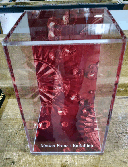 Clear acrylic trophy with red interior and a silver fan design, resting on a wooden surface.