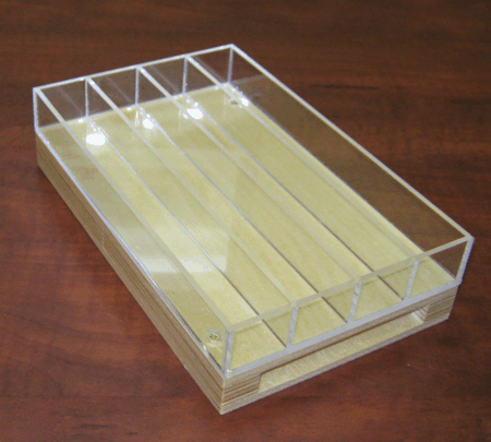 Clear acrylic display tray with four compartments on a wooden table