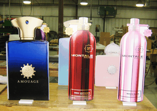 Three perfume bottles on a shelf, including blue Amouage, red Montale, and pink Montale bottles