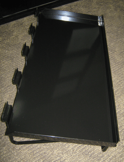 Black binder or portfolio lying open on a carpeted floor, with three clips visible on the left side.