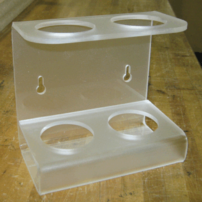 Clear acrylic wall-mounted holder with two cup-sized openings and keyhole slots on a wooden surface