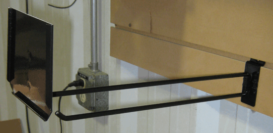 Wall-mounted black swing arm holding a flat-screen TV in a room with light wood cabinets.