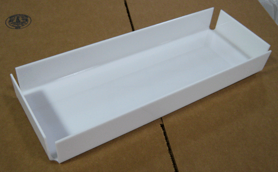 White rectangular cardboard tray on a brown surface, with raised sides and open top.