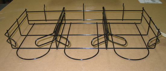 Black wire rack on a cardboard box with two coiled cords and raised side rails, on a tabletop.
