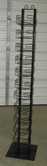 Tall black metal rack with multiple small shelves, standing against a light-colored wall on a carpeted floor.