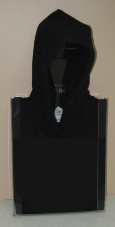 Black hoodie displayed in a clear rectangular case against a beige wall.