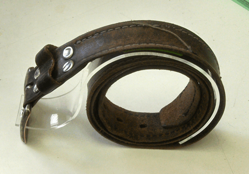 Brown leather belt rolled into a coil with a black buckle, isolated on a white background
