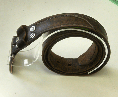 Brown leather strap with a clear curved shield, rolled into a loop on a white background