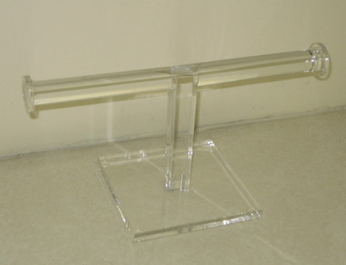 Clear acrylic stand holding a horizontal tube on a square base against a beige background