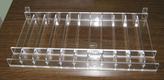 Clear acrylic display riser with multiple small compartments on a wooden surface