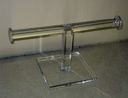Clear acrylic display stand holding a long cylindrical object on a tabletop.