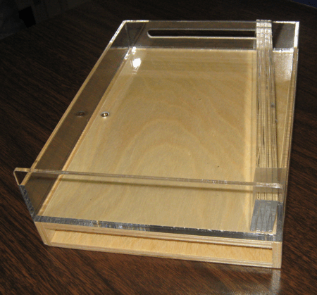 Clear acrylic box with a wooden base and transparent sliding lid on a dark surface