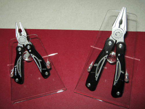 Two black Swiss Army knives displayed on clear stands against a red background