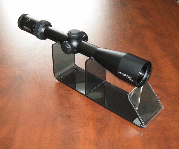 Black telescope mounted on a clear stand on a wooden table