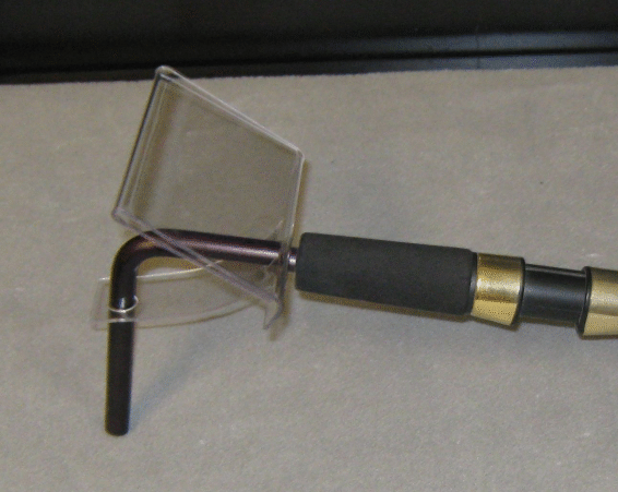 Transparent wheelchair tray attached to a black-and-gold handle with a small front wheel