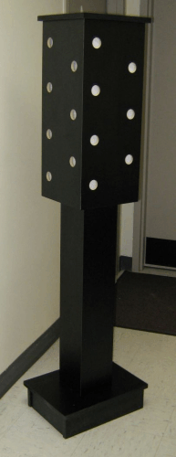 Black metal pedestal with perforated side panels on a square base in an indoor room.