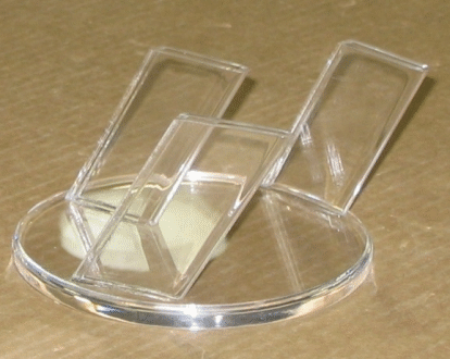 Clear acrylic business card holder on a round base, resting on a wooden surface.