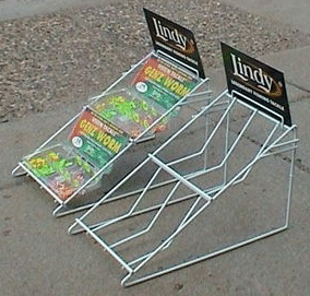 Wire rack magazine display with two empty shelves and Linda magazines on a concrete floor