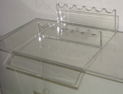 Clear acrylic display stands on a white surface with wavy top edges
