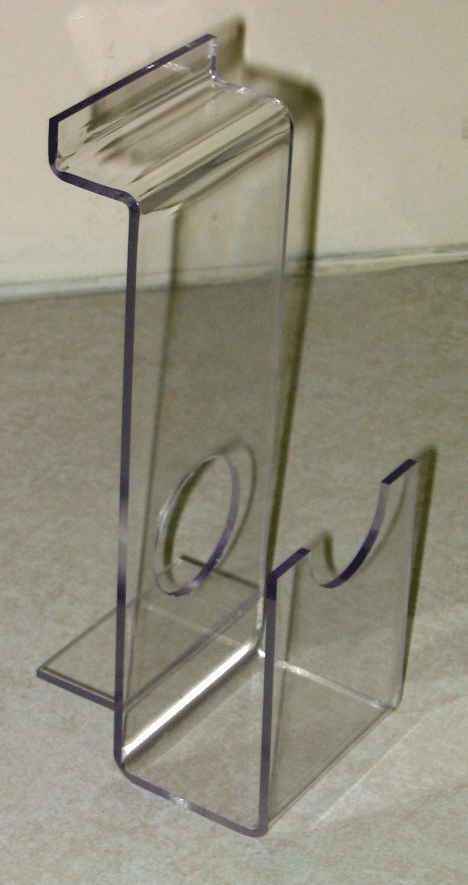 Clear acrylic brochure holder with a circular cutout, standing on a beige floor against a wall.