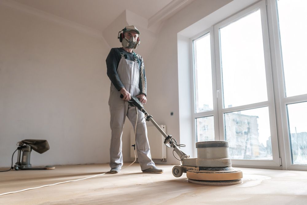 A Person Wearing Protective Gear Uses a Floor Sander on a Wood Floor  — Crystal Clear In Walcha, NSW