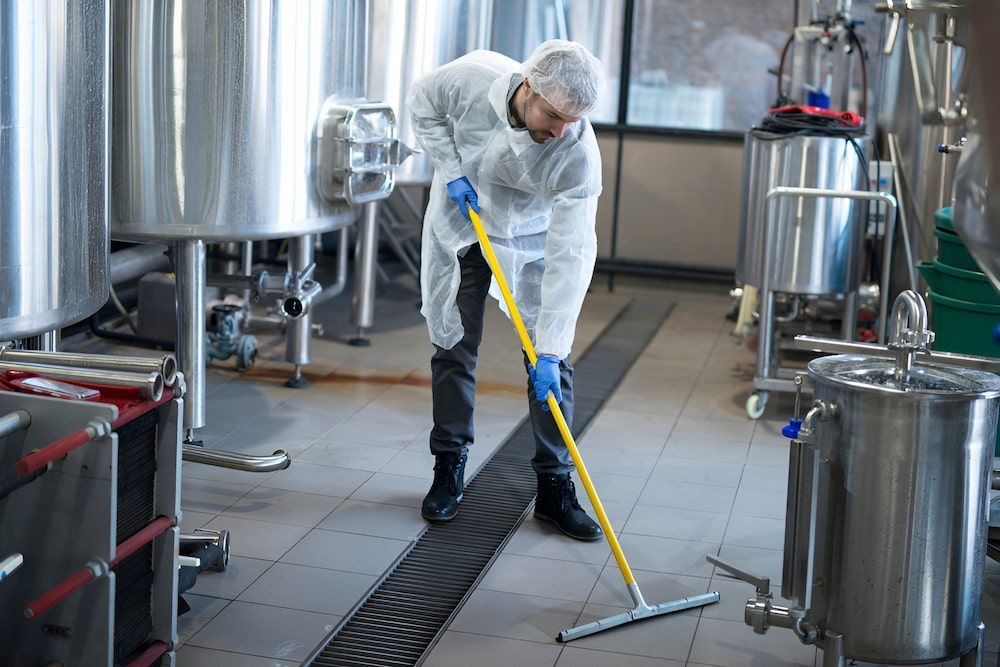 A Man Is Cleaning The Floor Of A Factory With A Mop — Crystal Clear In Armidale, NSW