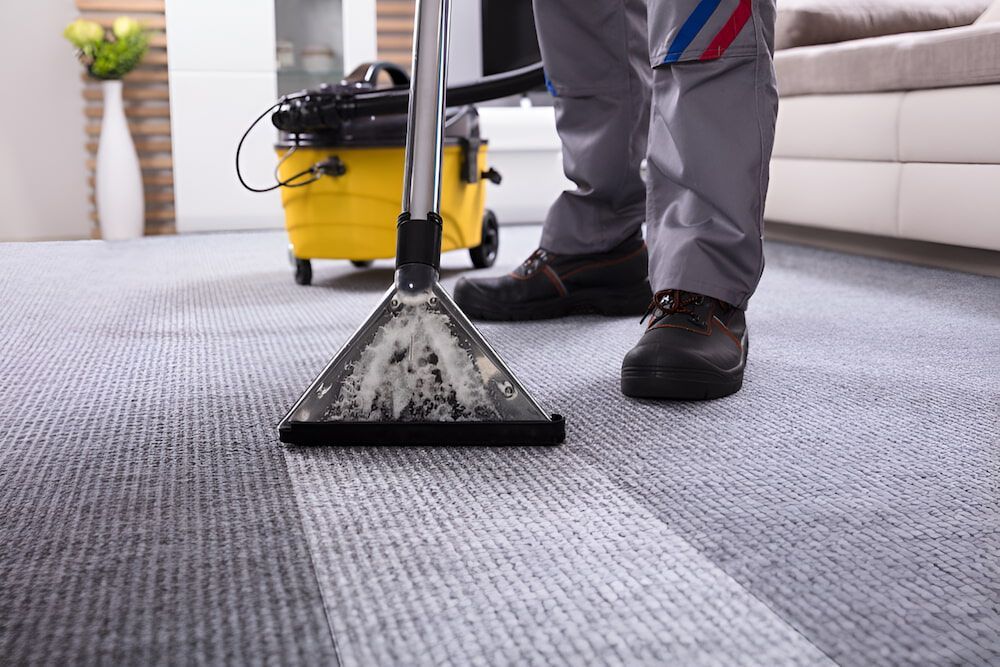 A Person Is Cleaning A Carpet With A Vacuum Cleaner — Crystal Clear In Armidale, NSW