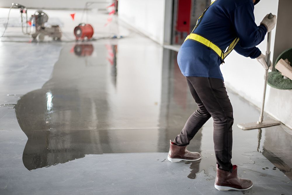 A Man Is Cleaning The Floor With A Mop — Crystal Clear In Armidale, NSW