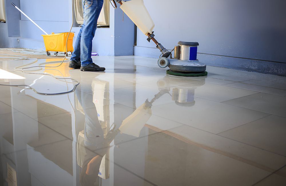 A Man Is Cleaning A Tiled Floor With A Machine — Crystal Clear In Uralla, NSW