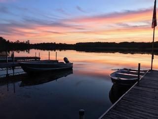 A sunset over a lake with boats docked at a dock.