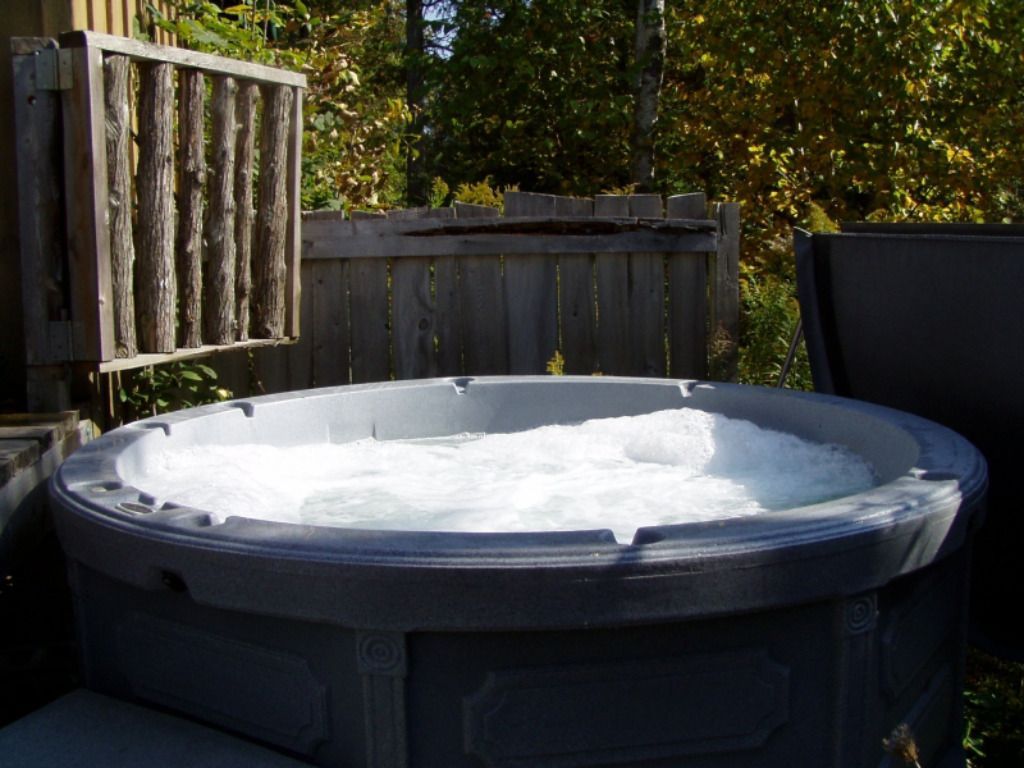 A hot tub with foam coming out of it in front of a wooden fence