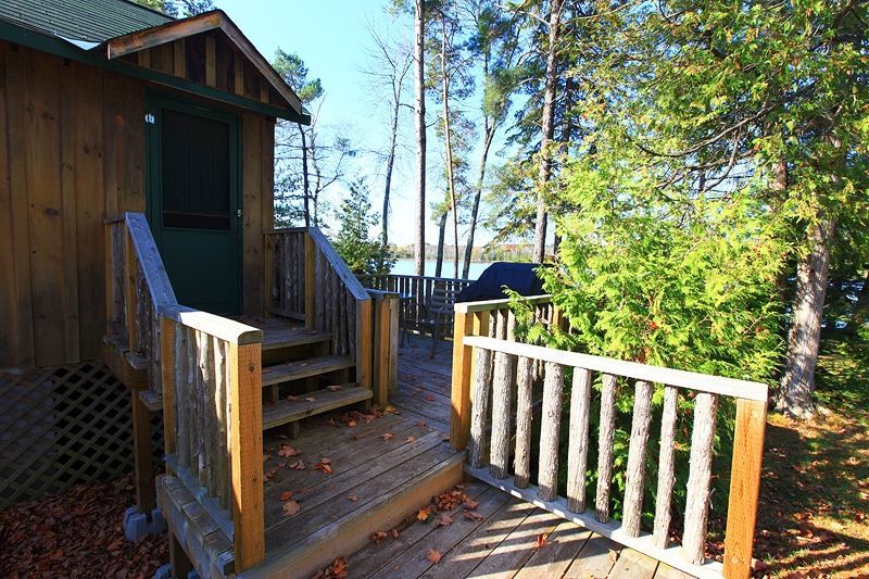 A wooden deck with stairs leading up to a cabin in the woods.