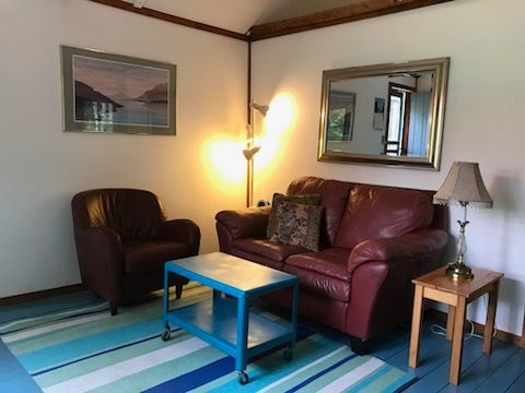 A living room with a couch , chair , table , lamp and mirror.