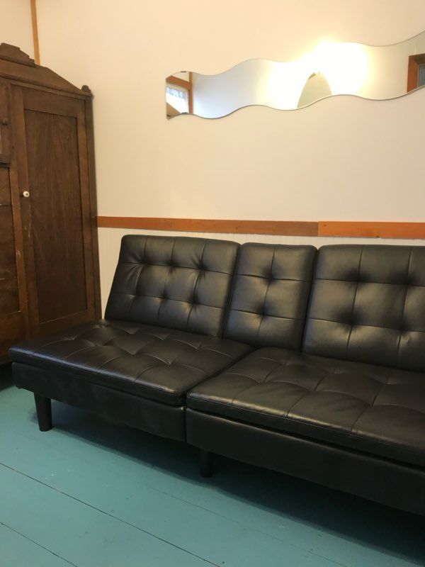 A black couch in a room with a mirror on the wall