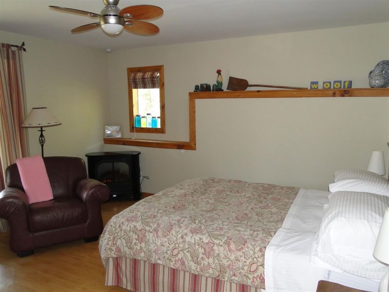 A bedroom with a bed a chair and a ceiling fan