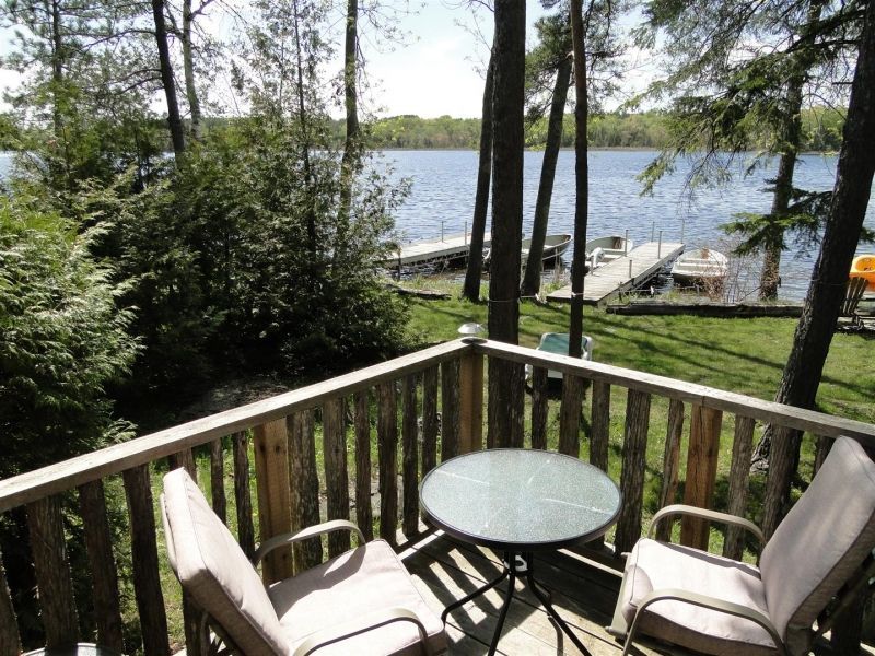 Two chairs and a table on a deck overlooking a lake