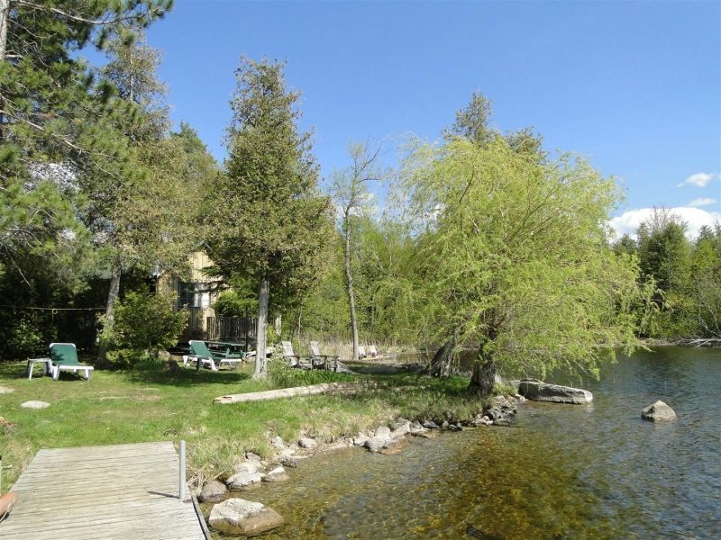 A dock leading to a lake with a house in the background