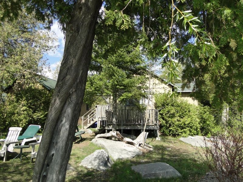 A house with a deck is surrounded by trees and rocks