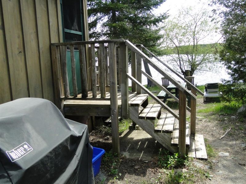 A weber grill sits next to a wooden deck