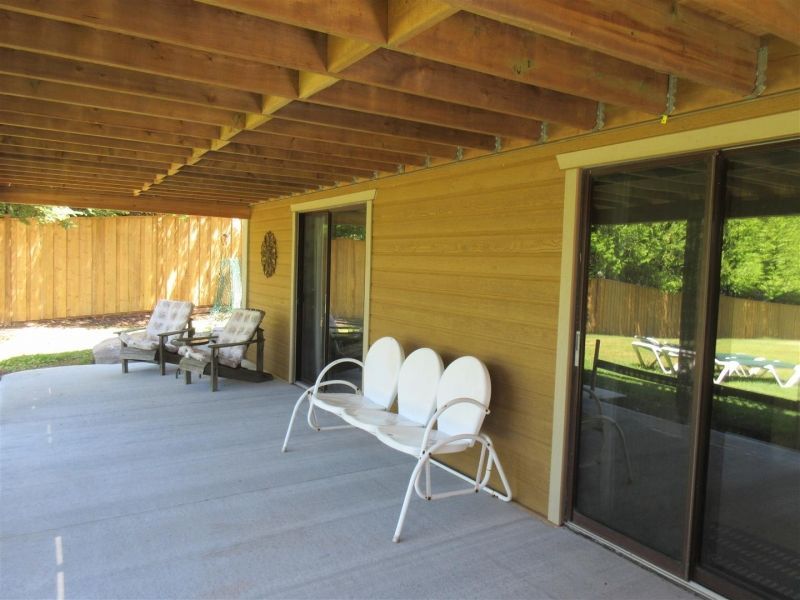 A patio with a bench and chairs and a sliding glass door