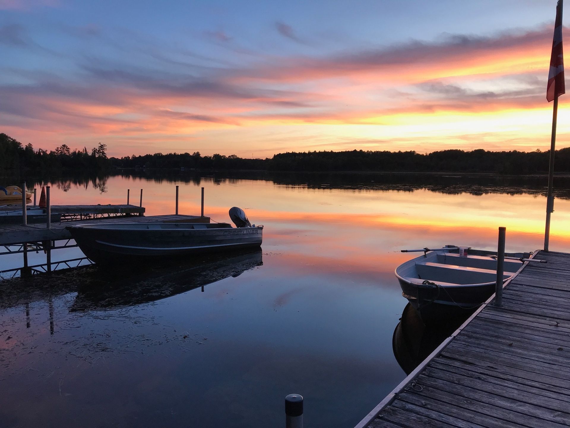 A sunset over a lake with boats docked at a dock