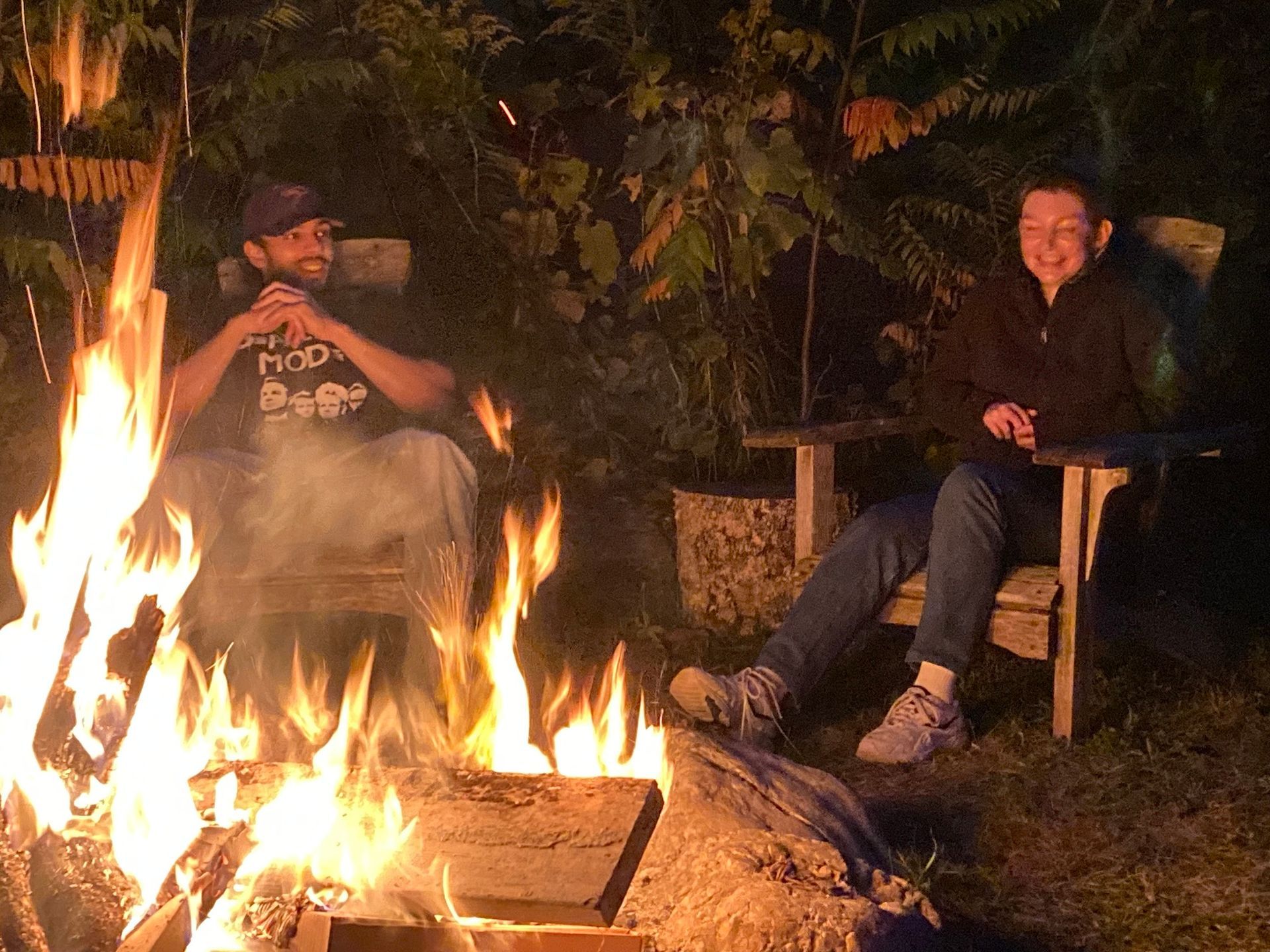Two people are sitting around a fire at night