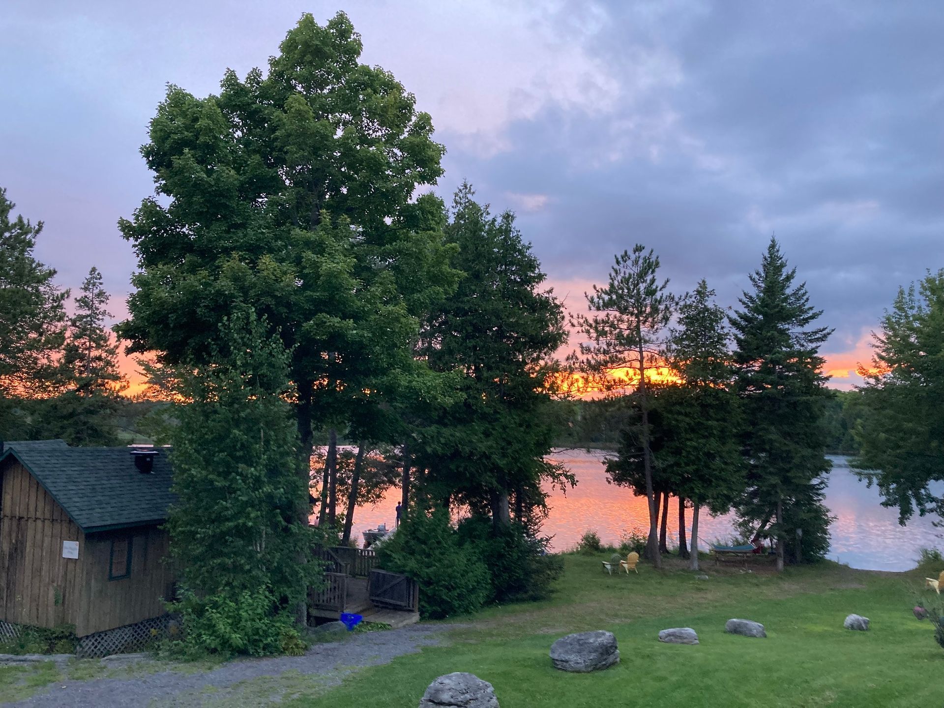 A sunset over a lake with a cabin in the foreground