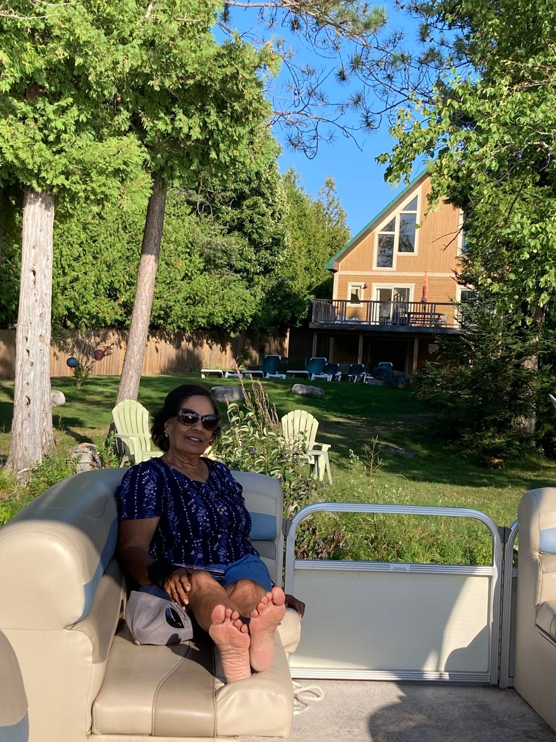 A woman is sitting on a pontoon boat in front of a house.