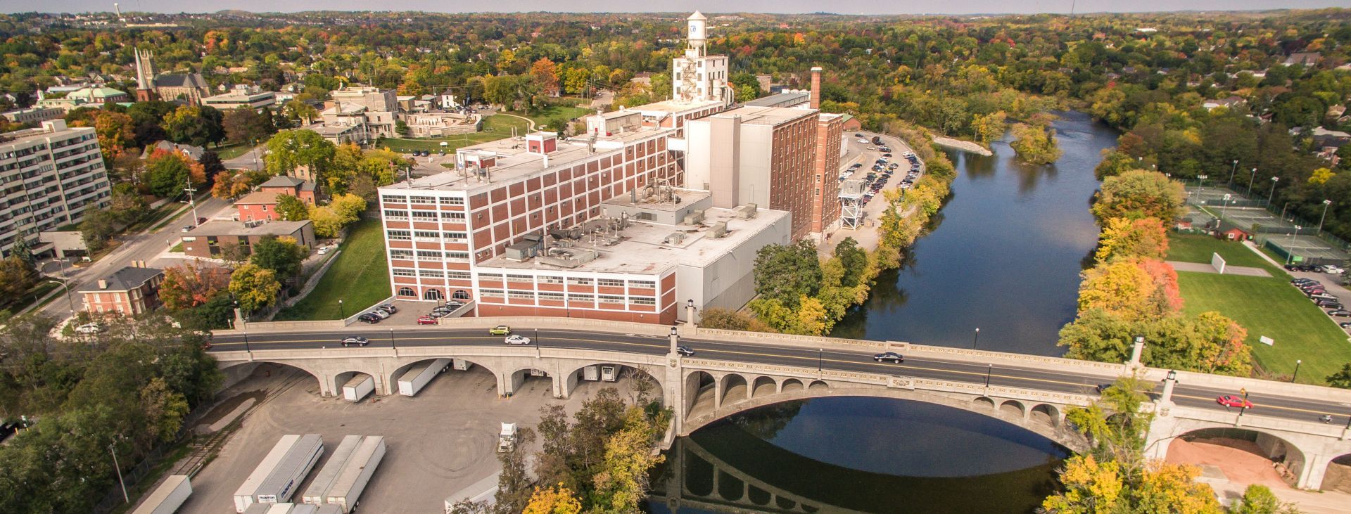 Aerial view of a city with a river, bridge, and industrial buildings in fall.