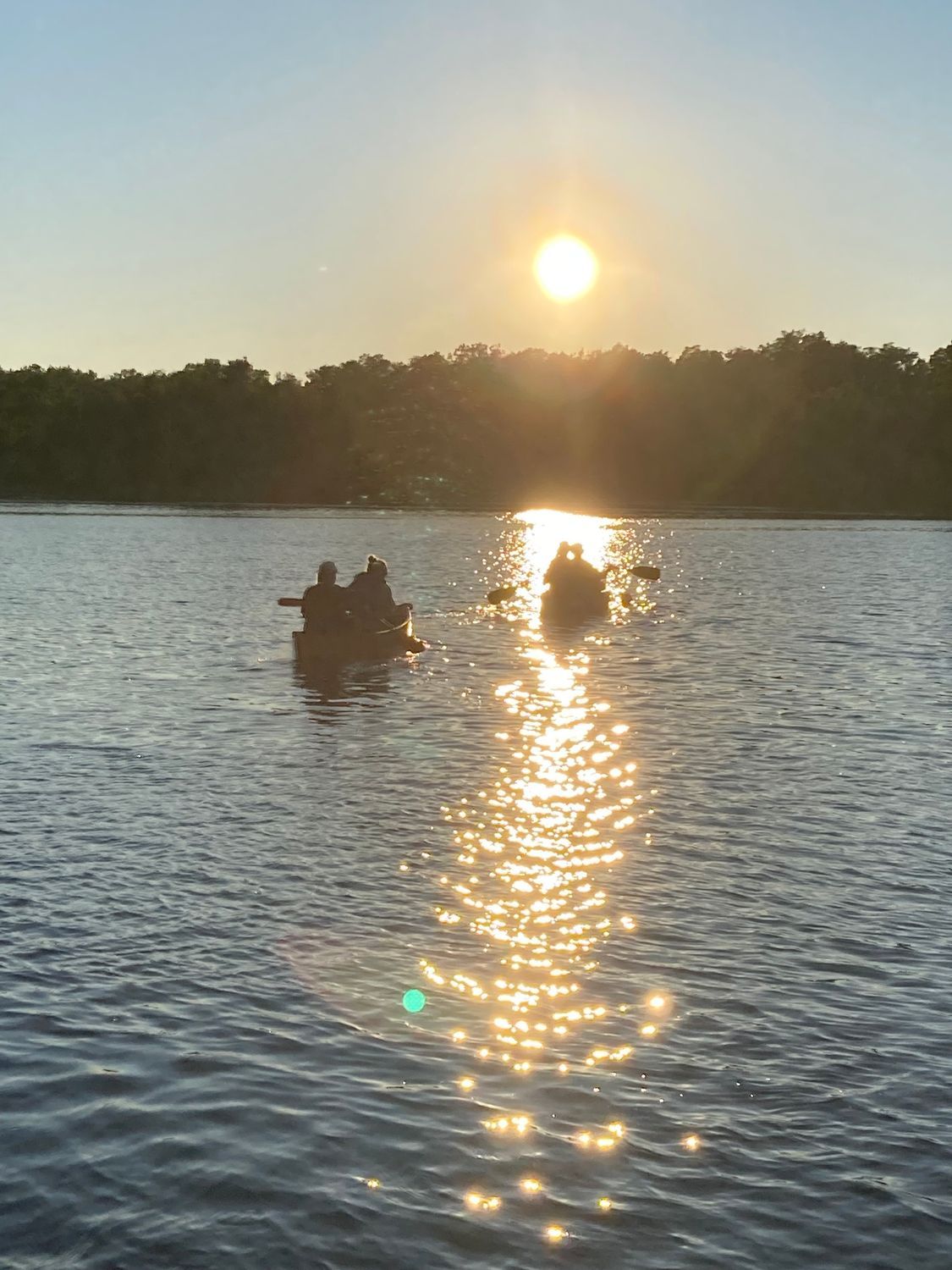 A group of people in a boat on a lake at sunset